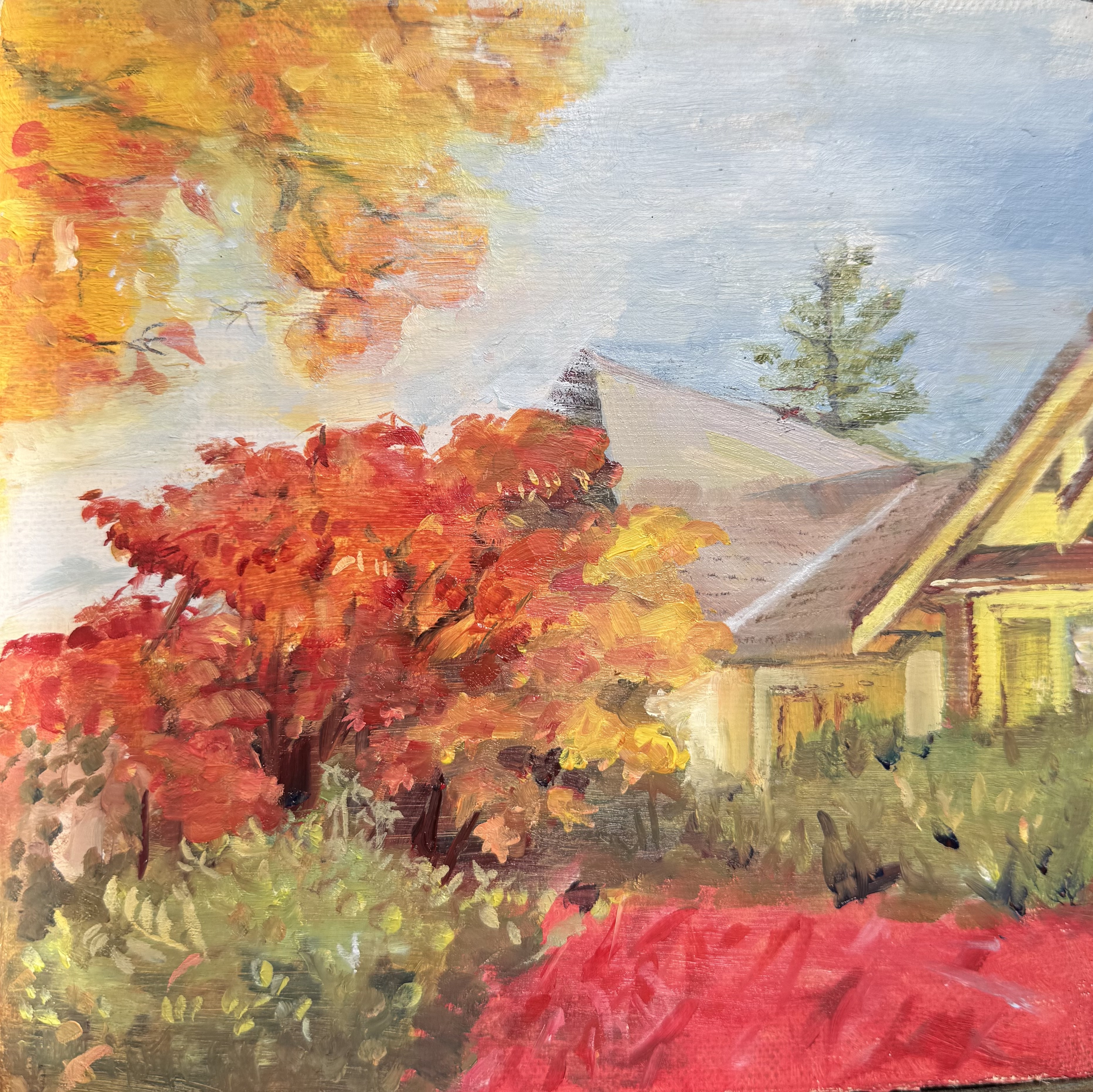 Red and orange autumn trees beside a yellow house
